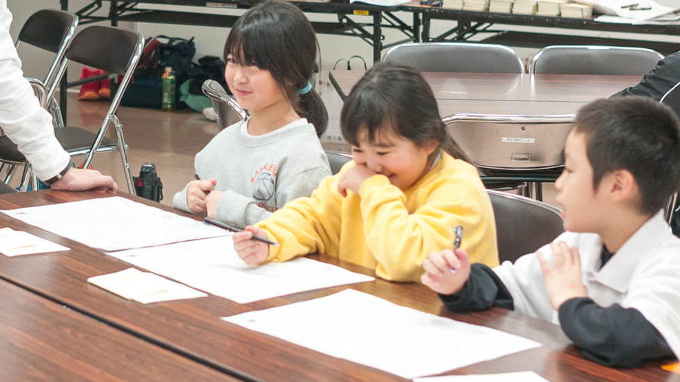 9マスノートに鉛筆で夢や目標を書き込む子どもたち