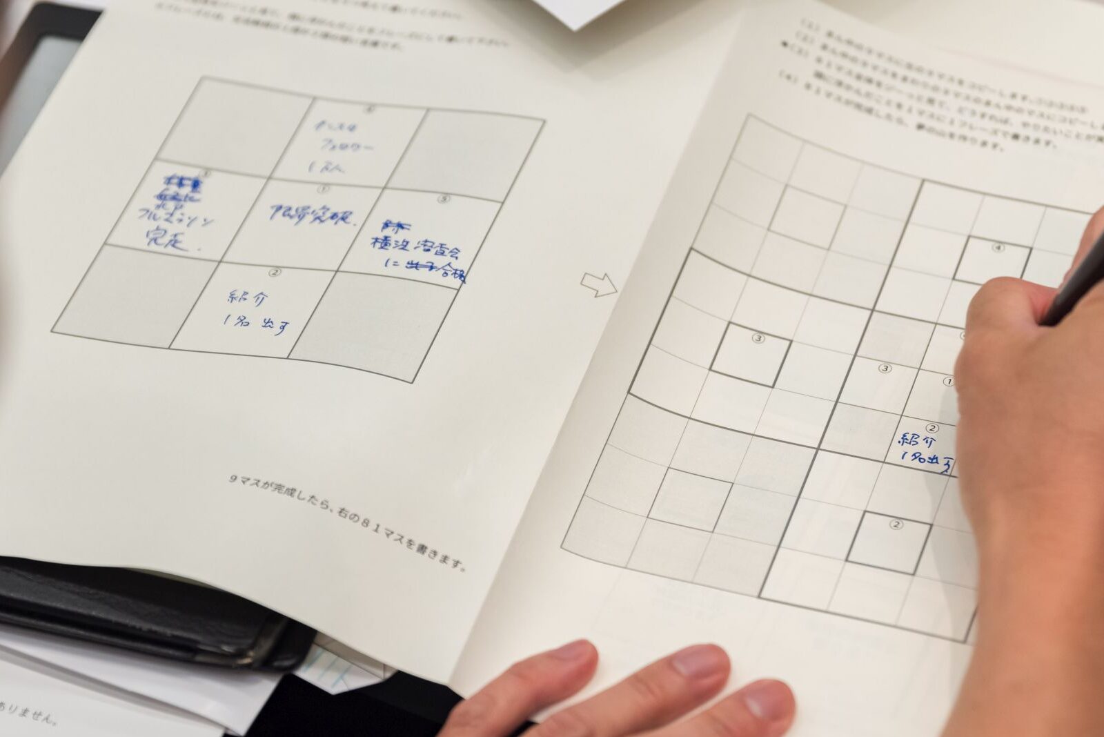 9マスノートに青色のペンで目標を書き込む企業研修の参加者
